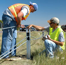 Workers installing a cable median barrier.