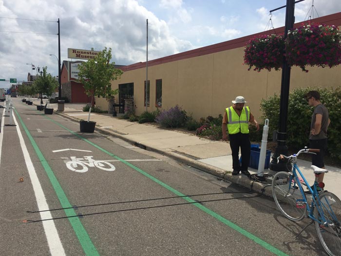 Two people installing bicycle and pedestrian counters along a road and sidewalk in Alexandria, Minnesota.