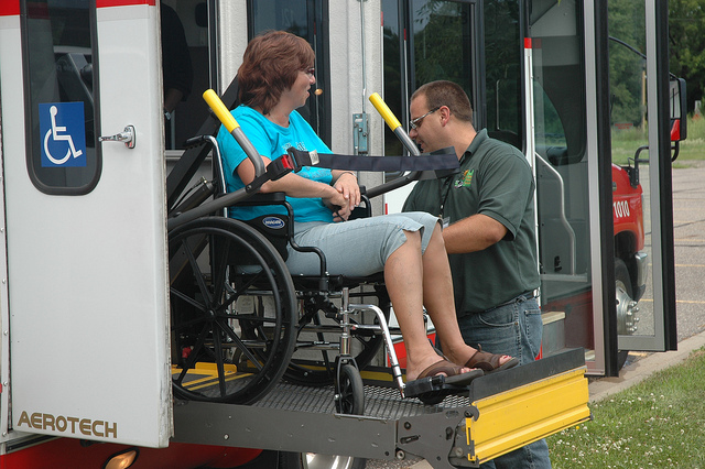 A differently abled person getting on a bus in a wheelchair